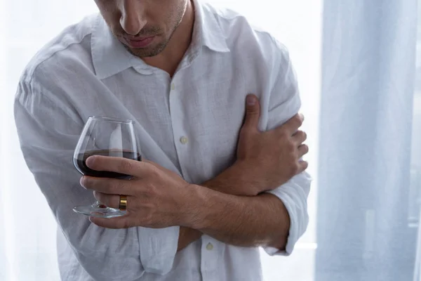 Partial view of man in shirt holding glass of cognac — Stock Photo