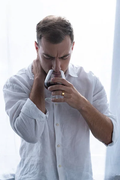 Front view of depressed man in shirt drinking cognac at home — Stock Photo