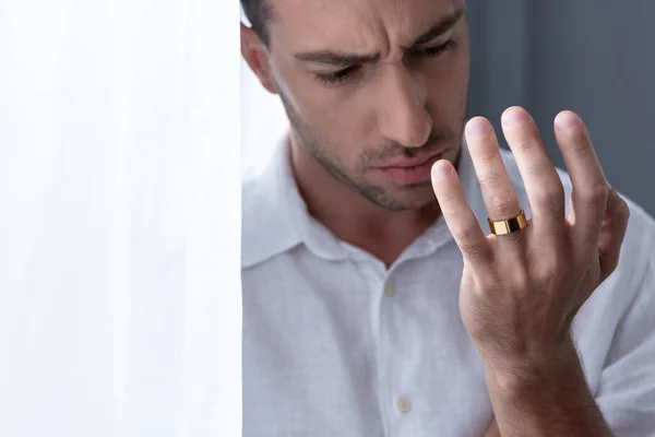 Depressiver Mann im weißen Hemd blickt auf Ring am Finger — Stockfoto