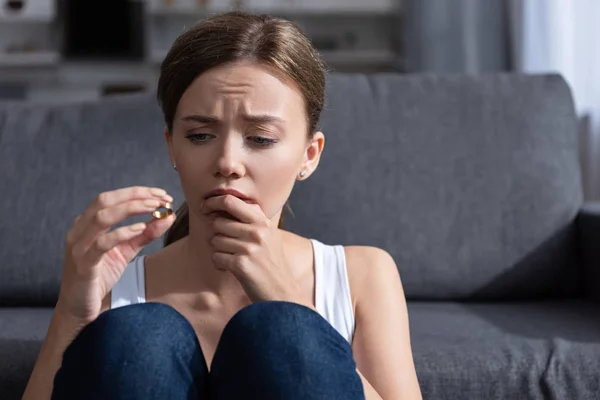 Upset young woman holding ring in living room at home — Stock Photo