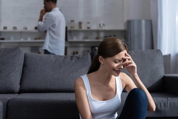 Llorando mujer joven en sofá y hombre en camisa blanca - foto de stock