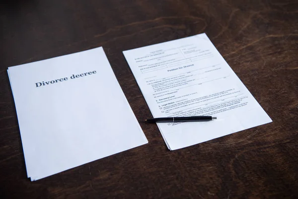 Documentos de divorcio y pluma sobre mesa de madera marrón - foto de stock