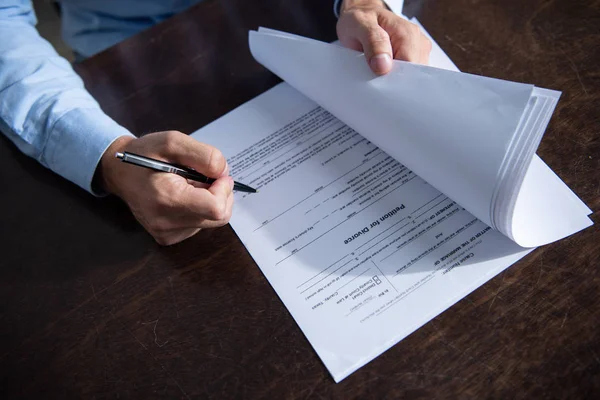 Partial view of man sitting at table and signing divorce documents — Stock Photo