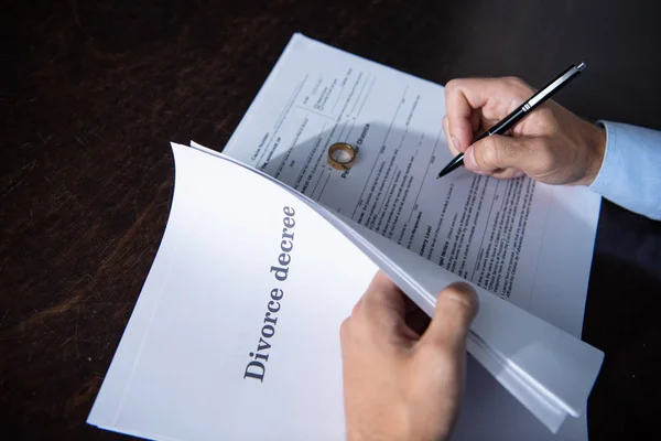 Vista parcial del hombre sentado en la mesa y firmando documentos de divorcio - foto de stock