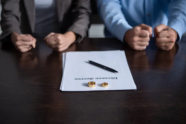 Vue partielle du couple serrant les poings à table avec documents de divorce — Photo de stock