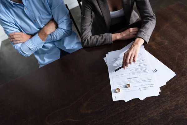 Vista parcial de la pareja en la mesa con documentos de divorcio - foto de stock