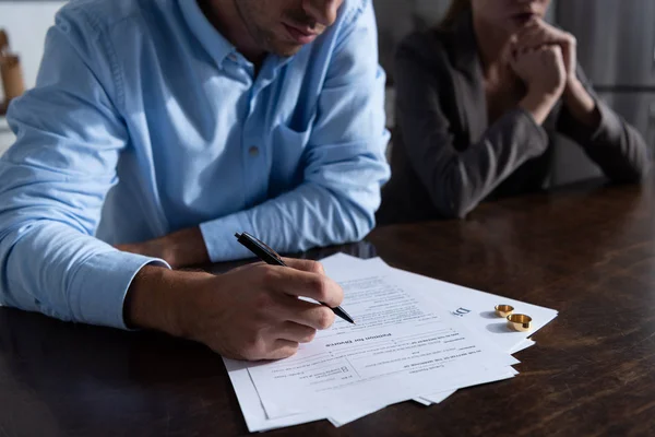 Vista parcial de la pareja en la mesa con documentos de divorcio - foto de stock