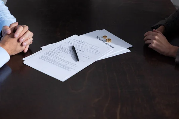 Частичный взгляд пары за столом с документами о разводе — стоковое фото