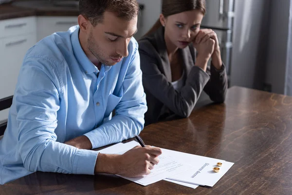 Pareja con documentos de divorcio en la mesa en casa - foto de stock