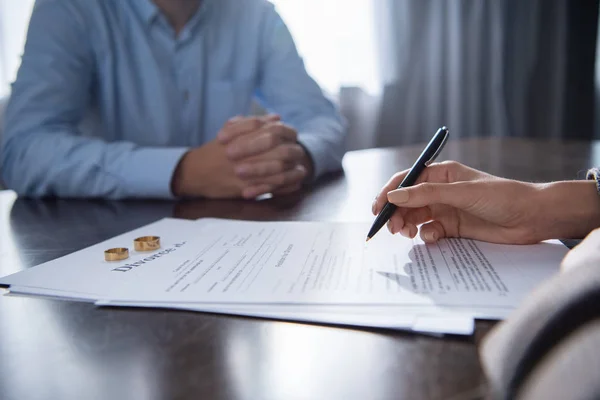 Vista parcial de la pareja en la mesa con documentos de divorcio - foto de stock