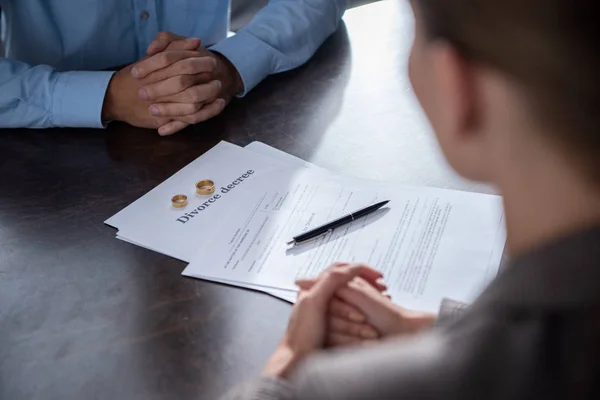 Vista parcial de la pareja en la mesa con documentos de divorcio - foto de stock