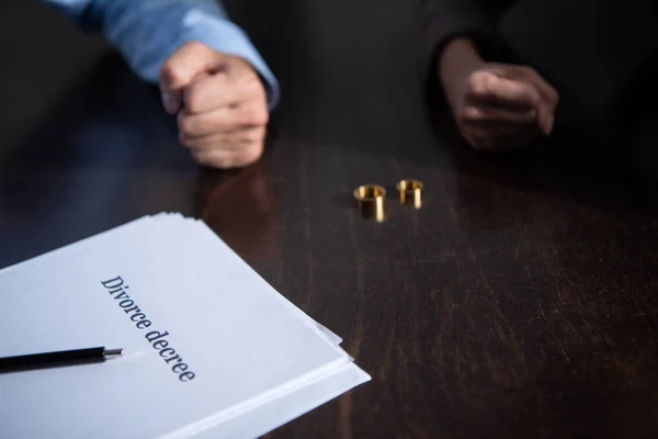 Visão parcial do casal à mesa com documentos de divórcio e anéis — Fotografia de Stock