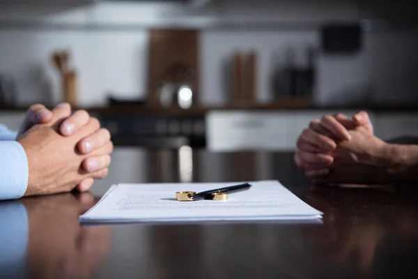 Vue partielle du couple assis à table les mains serrées près des documents de divorce — Photo de stock