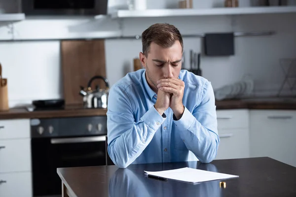 Hombre triste en camisa sentado en la mesa con el anillo y los documentos de divorcio - foto de stock