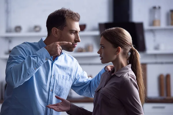 Hombre enojado señalando con el dedo a la esposa durante la pelea - foto de stock