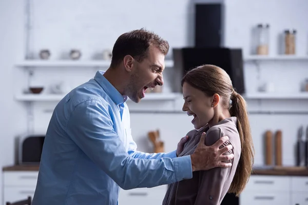 Side view of aggressive man in shirt screaming at wife during quarrel — Stock Photo