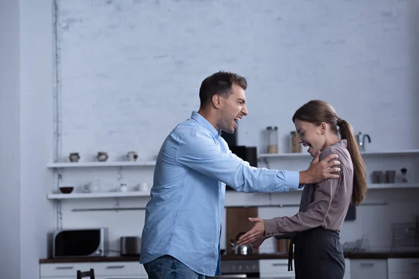 Vista lateral del hombre agresivo en camisa gritando a la esposa durante la pelea - foto de stock