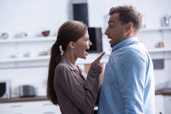 Seitenansicht einer wütenden Frau, die mit dem Finger zeigt und ihren Mann anschreit — Stockfoto