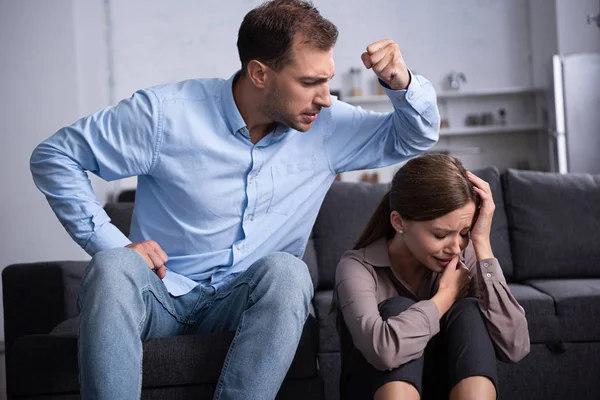 Agresivo hombre en camisa golpeando asustado esposa durante pelea - foto de stock