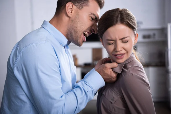 Aggressive man in shirt screaming at scared wife at home — Stock Photo