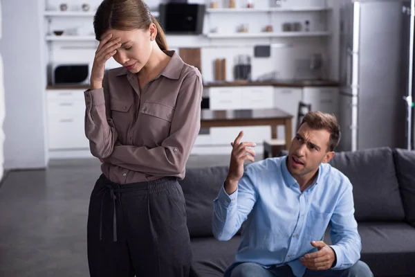 Traurige müde Frau und wütender Mann zu Hause auf dem Sofa sitzend — Stockfoto