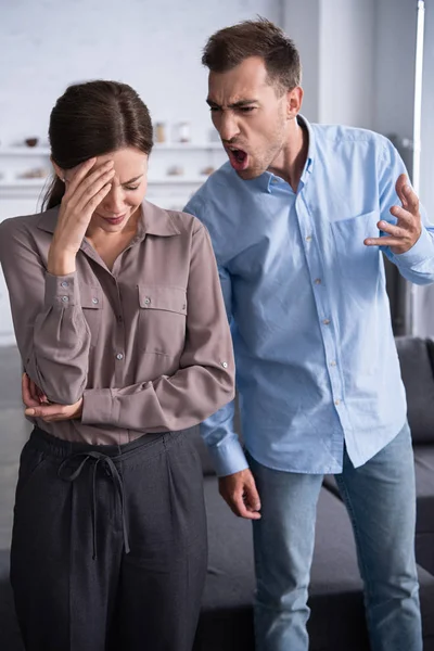 Uomo aggressivo in camicia urlando a moglie spaventata a casa — Foto stock