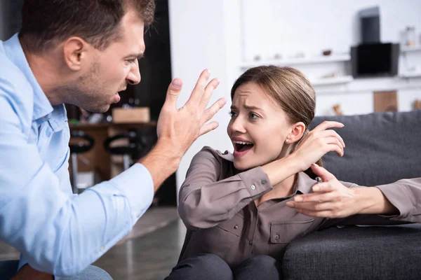 Homem agressivo na camisa gritando com a esposa assustada em casa — Fotografia de Stock