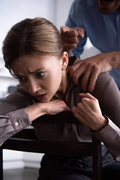 Partial view of man beating scared wife at home — Stock Photo