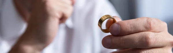 Panoramic shot of man holding ring and propping face with hand — Stock Photo