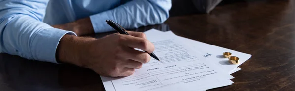 Panoramic shot of man signing divorce documents at table — Stock Photo