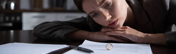 Panoramic shot of sad woman at table with ring and documents — Stock Photo