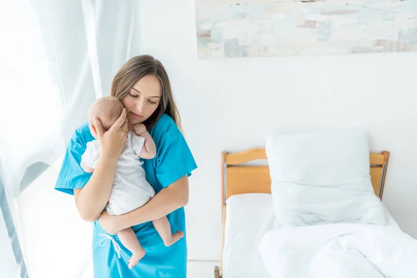 Atraente e jovem mãe segurando seu filho no hospital — Fotografia de Stock