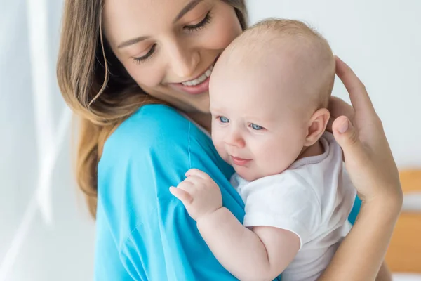 Attraente e giovane madre che tiene il bambino in ospedale — Foto stock