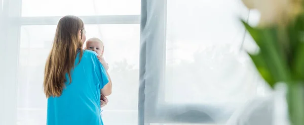 Panoramic shot of young mother holding her child in hospital — Stock Photo