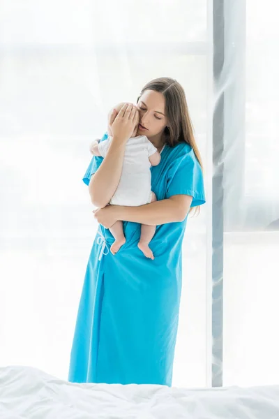 Atraente e jovem mãe segurando seu filho no hospital — Fotografia de Stock