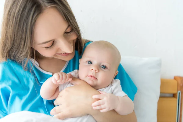 Attraente e giovane madre che tiene il bambino in ospedale — Foto stock