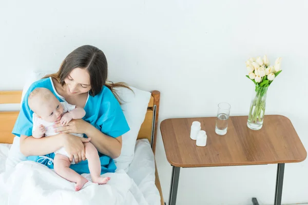 Привлекательная и молодая мать, держащая ребенка в больнице — стоковое фото
