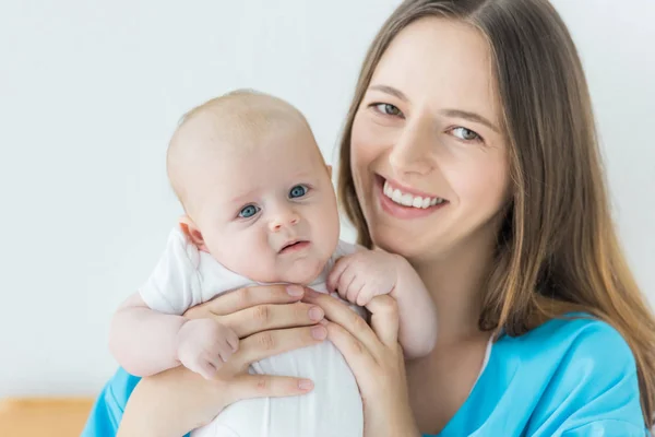 Attraktive und lächelnde Mutter mit ihrem Kind im Krankenhaus — Stockfoto