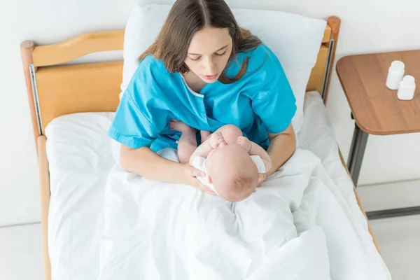 Высокий угол обзора привлекательной и молодой матери, держащей своего ребенка в больнице — стоковое фото