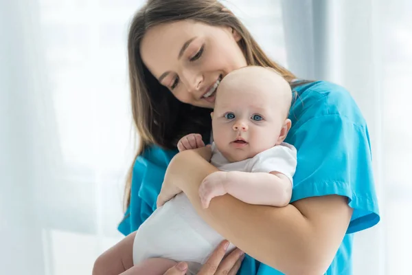 Atraente e jovem mãe segurando seu filho no hospital — Fotografia de Stock