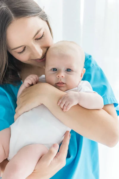 Attraente e giovane madre che tiene il bambino in ospedale — Foto stock