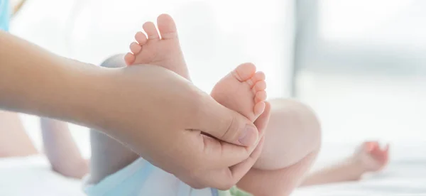 Plano panorámico de la madre sosteniendo las piernas de su hijo - foto de stock