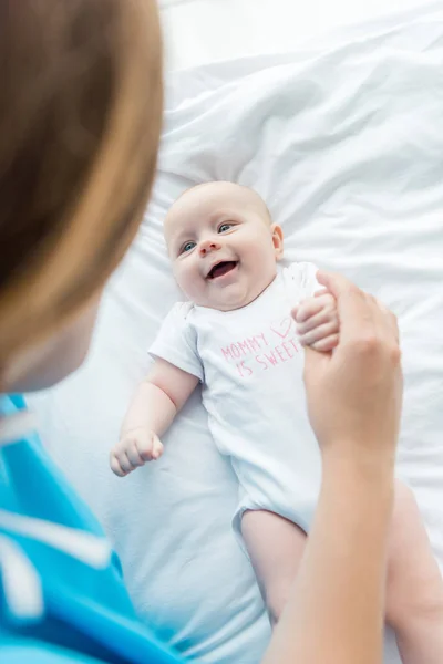 Enfoque selectivo de bebé lindo mirando a la madre en el hospital - foto de stock