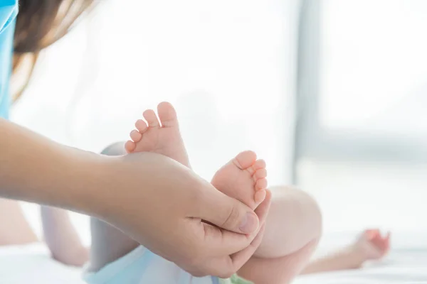 Cropped view of mother holding legs of her child — Stock Photo