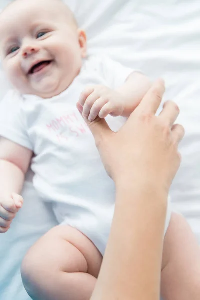 Vista recortada de la madre sosteniendo la mano de su bebé en el hospital - foto de stock