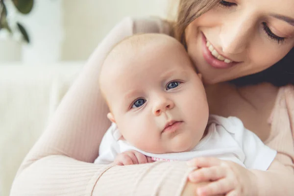 Vista ritagliata di madre che tiene il suo bambino in appartamento — Foto stock