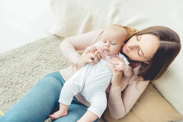 Blickwinkel der attraktiven Mutter, die ihr Kind in der Wohnung hält — Stockfoto