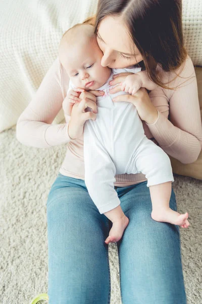 Visão de alto ângulo de mãe atraente segurando e beijando seu filho no apartamento — Fotografia de Stock