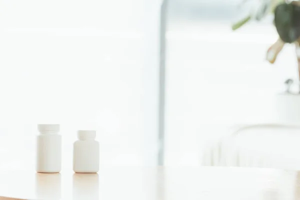 Selective focus of white bottles with pills on wooden table — Stock Photo