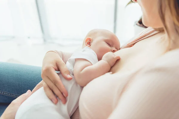 Cropped view of mother breastfeeding her child in apartment — Stock Photo